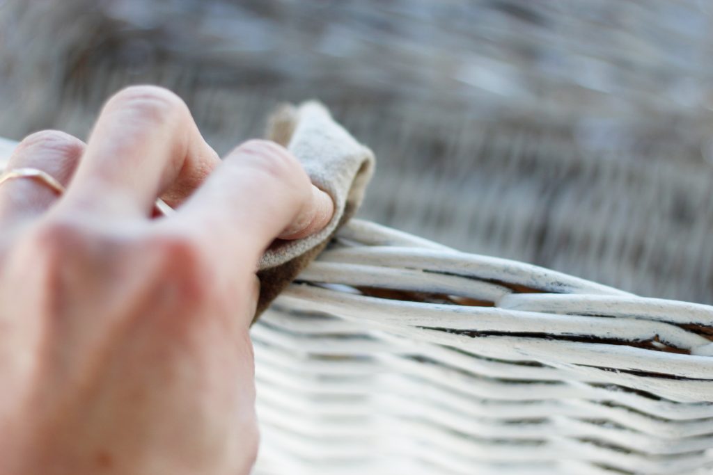 Picture of a hand putting wax on a painted basket