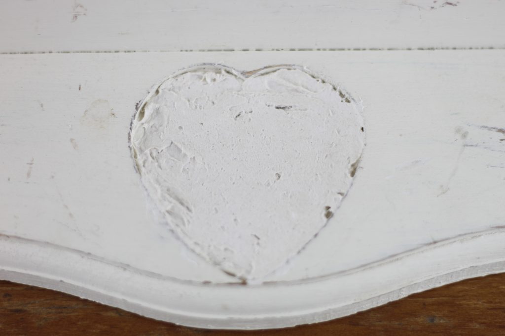 image of paper mache clay dried filling in a hole on a white wooden shelf