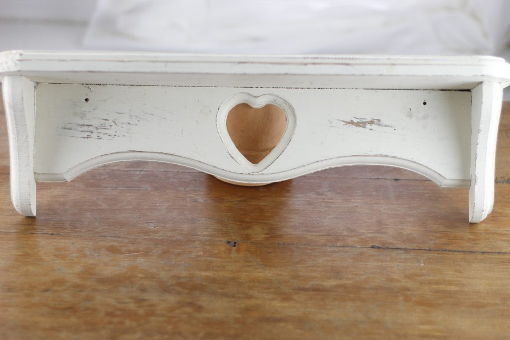 picture of a white distressed wooden shelf on a table