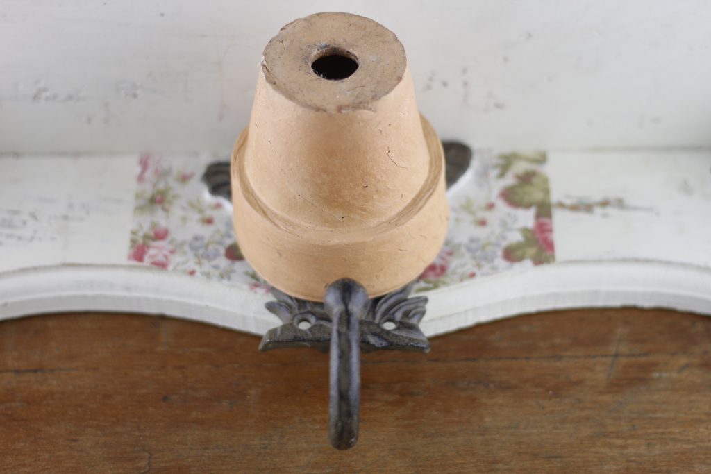 picture of shelf, and clay pot holding the hook in place as the paper mache clay dries