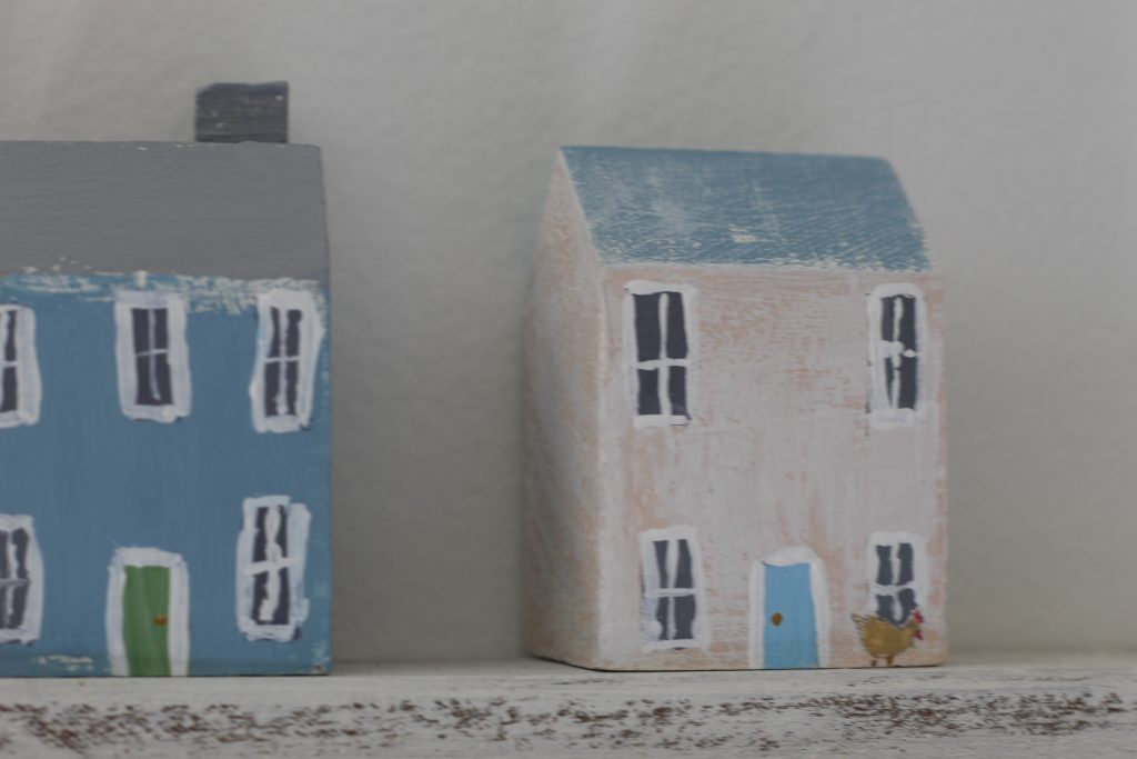 image of a white washed house with a blue roof with a chicken painted on the house