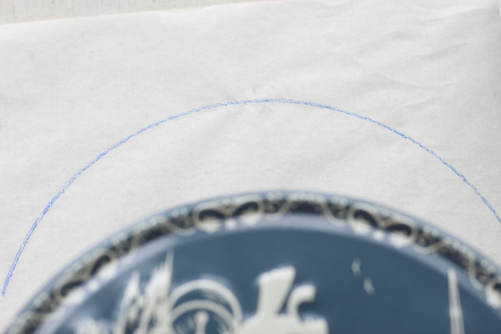 image of a curved blue line drawn on white paper and a blue tin 