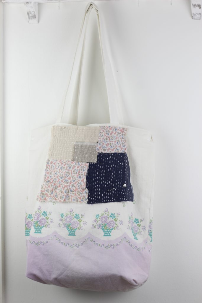 image of a hand-sewn boro patch pinned onto a floral fabric tote bag