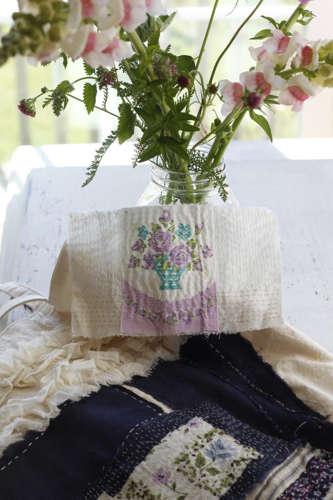 picture of vase of flowers and hand sewn boro patch resting on a white table