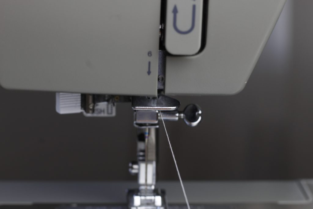 close-up picture of thread in position on the sewing machine as it is being threaded