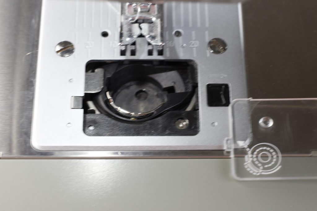 picture of the portion of the sewing machine that has been opened showing where the bobbin is to be inserted