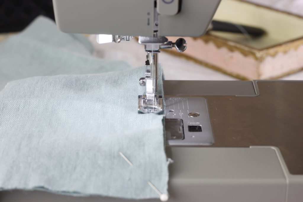 picture showing green fabric being sewn together with a sewing machine