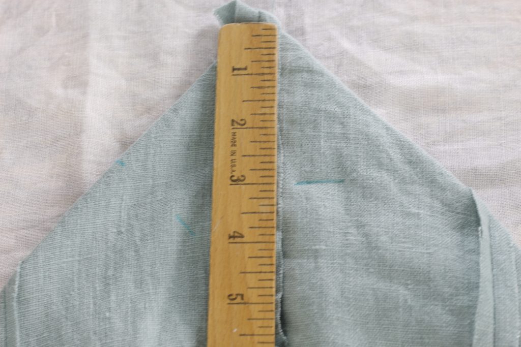 close-up picture of fabric being measured and marked with blue fabric marking pen