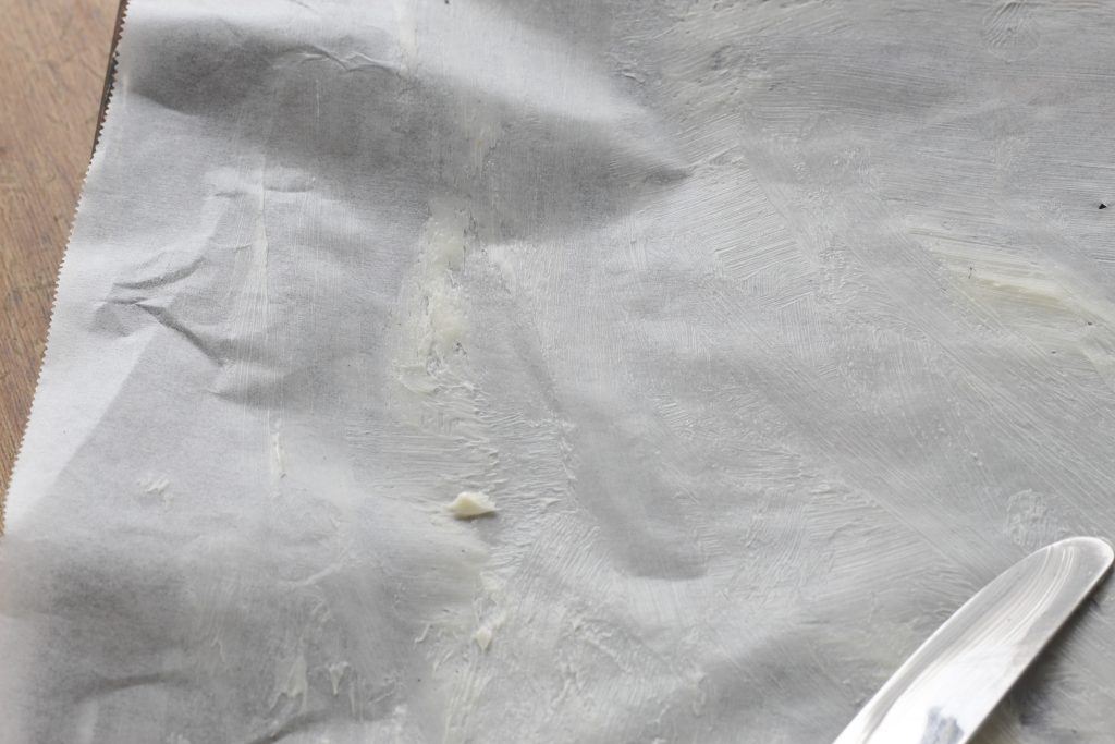 image of buttered parchment paper on a baking sheet