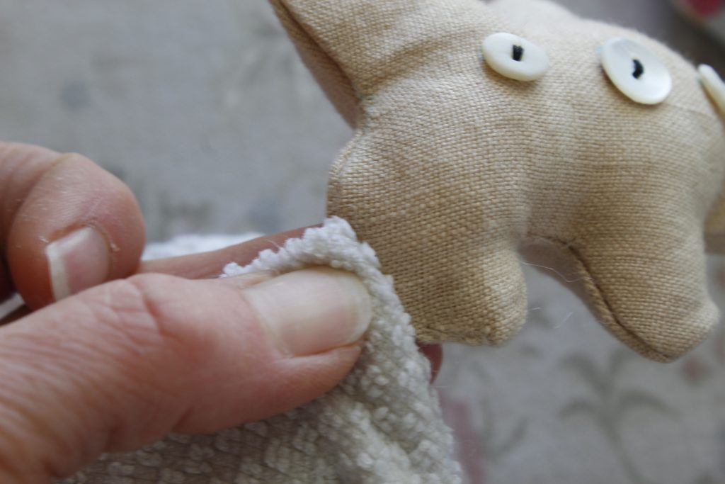 close-up image of a hand applying a damp cloth to fabric to remove water soluble marks