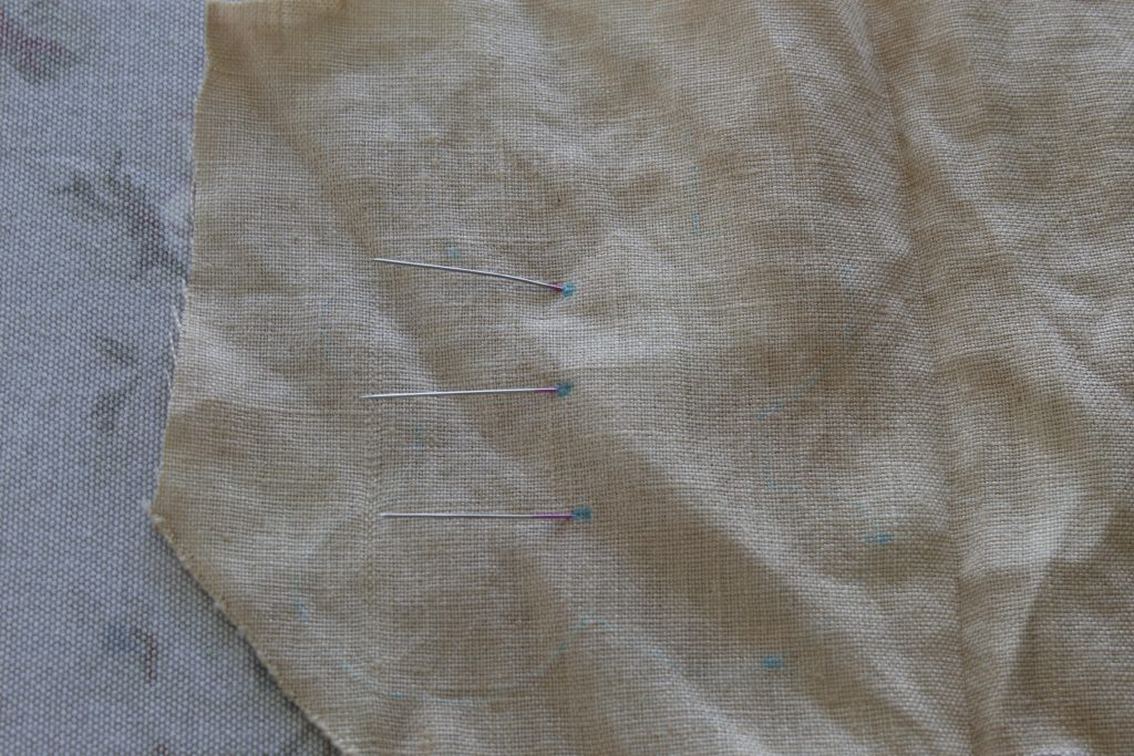 image of pins sticking out of fabric where fabric has been marked with blue dots