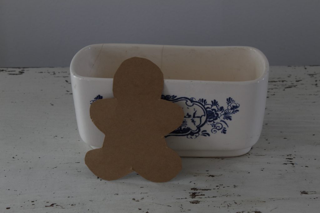 image showing gingerbread man sewing pattern cut out and leaning against white and blue piece of china