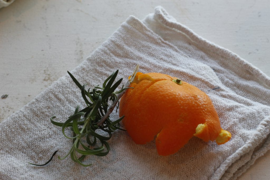image of a sprig of rosemary and an orange peel lying on a cloth side by side