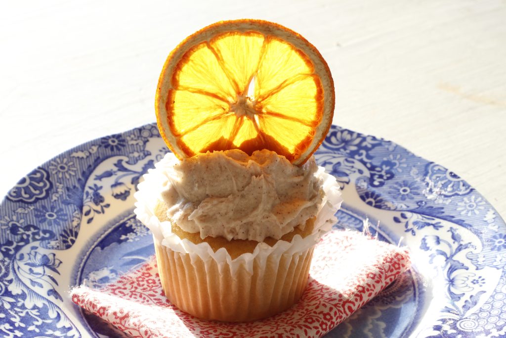 image of a an dried orange slice decorating a cupcake placed on a red and white cloth on a blue and white plate