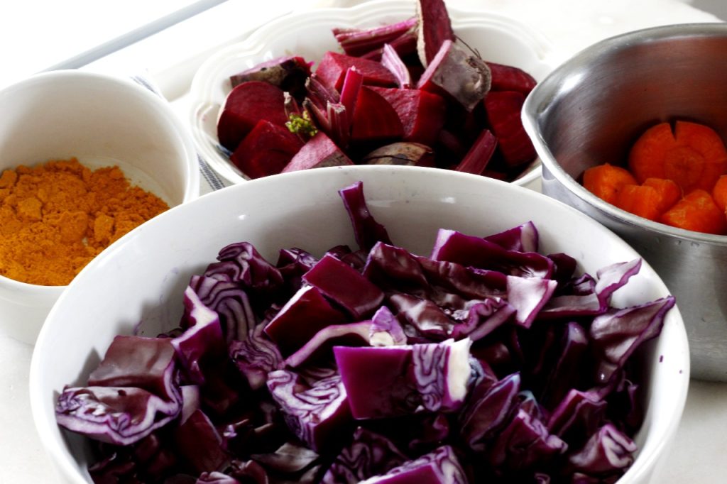 image showing bowls and a saucepan holding cut and measured red cabbage, carrots, beets, and turmeric to be used for plant dyes 