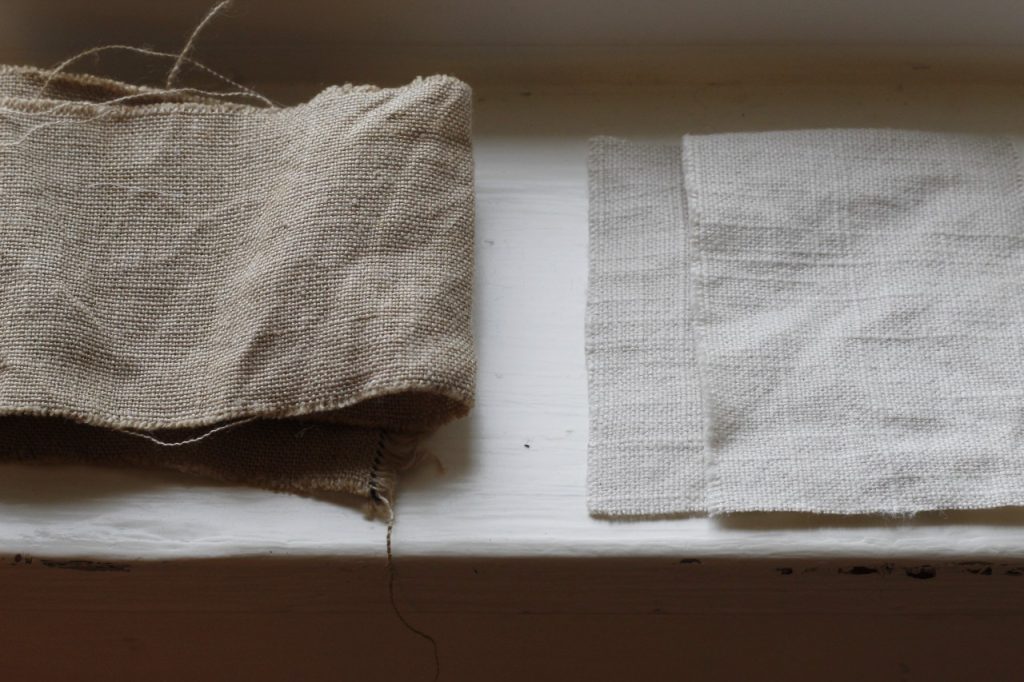close up image of a tan scrap of linen fabric and white scraps of linen fabric  on a white surface showing that scraps can be saved for sewing projects like this one