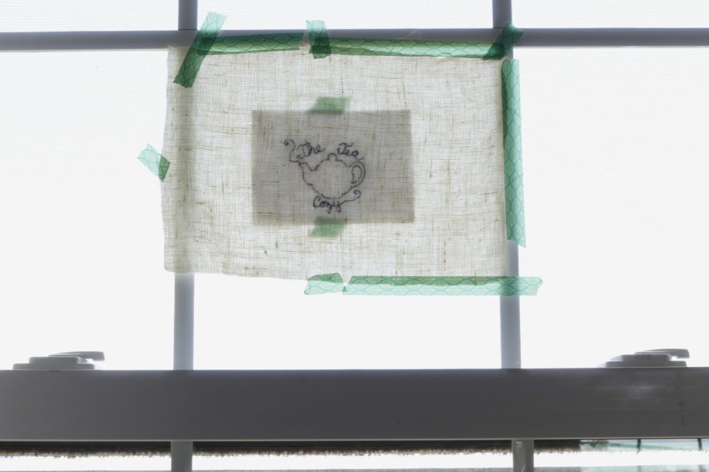 This is an image of an embroidery design taped to a window acting as a light box to transfer the design.