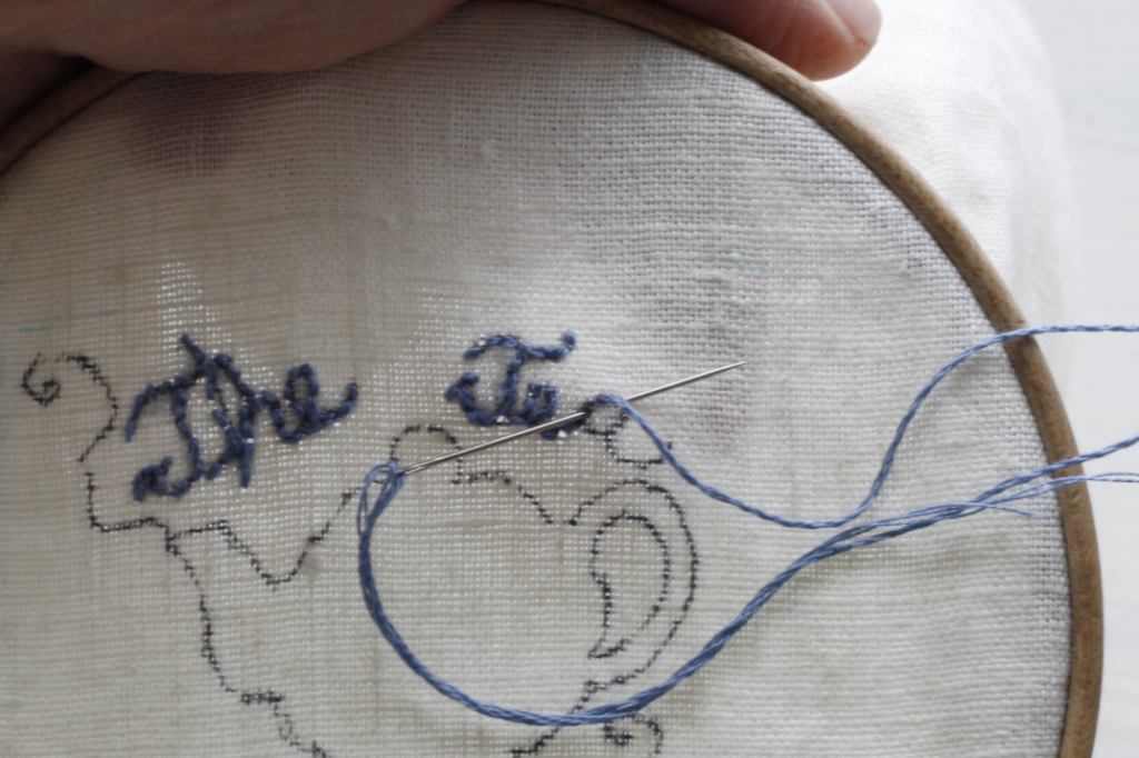 This is an image of a letter "A" in the word Tea being embroidered with blue thread.