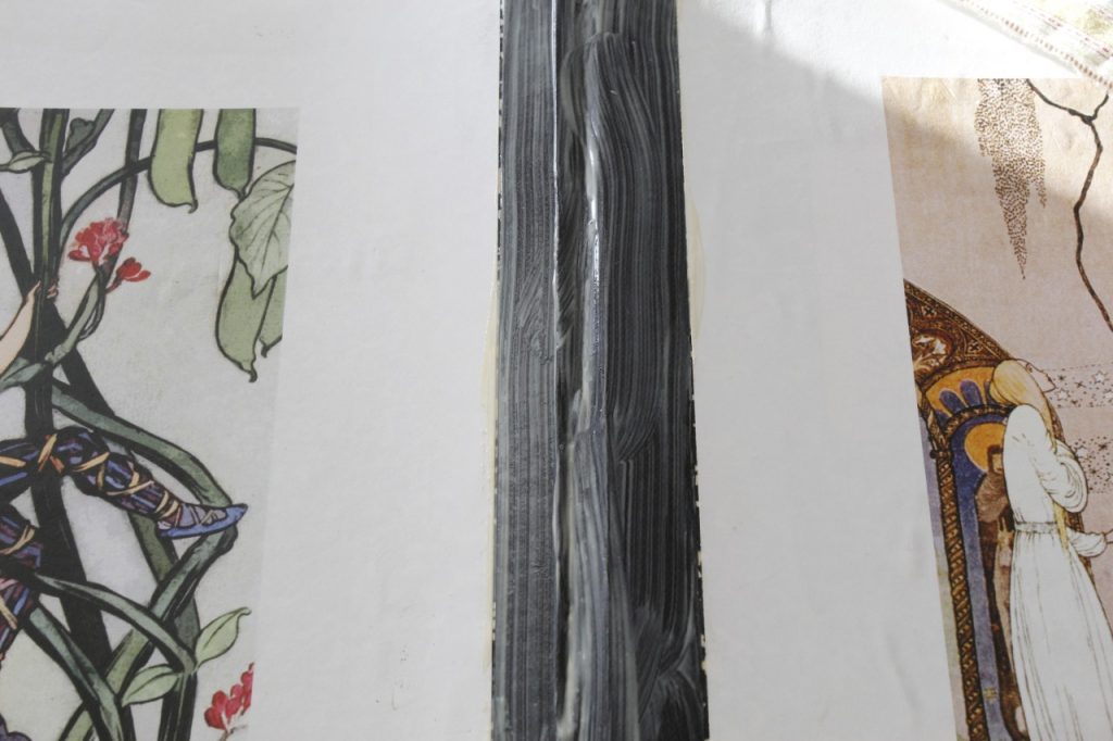 This is an image of the outside of the notebook opened up and both covers are covered with pictures of fairy-tales and showing the spine of the notebook has a layer of glue has been applied.
