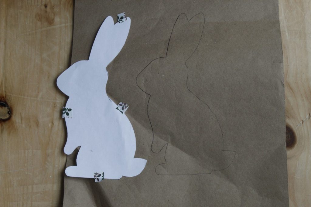 This image shows the white paper bunny moved off the brown paper and to the side indicating that it has been traced.