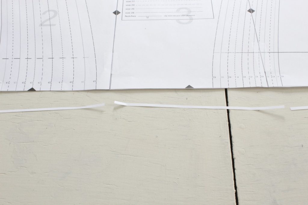 This image shows a strip of paper has been cut off the bottom of the sewing pattern, showing the reader where to cut.