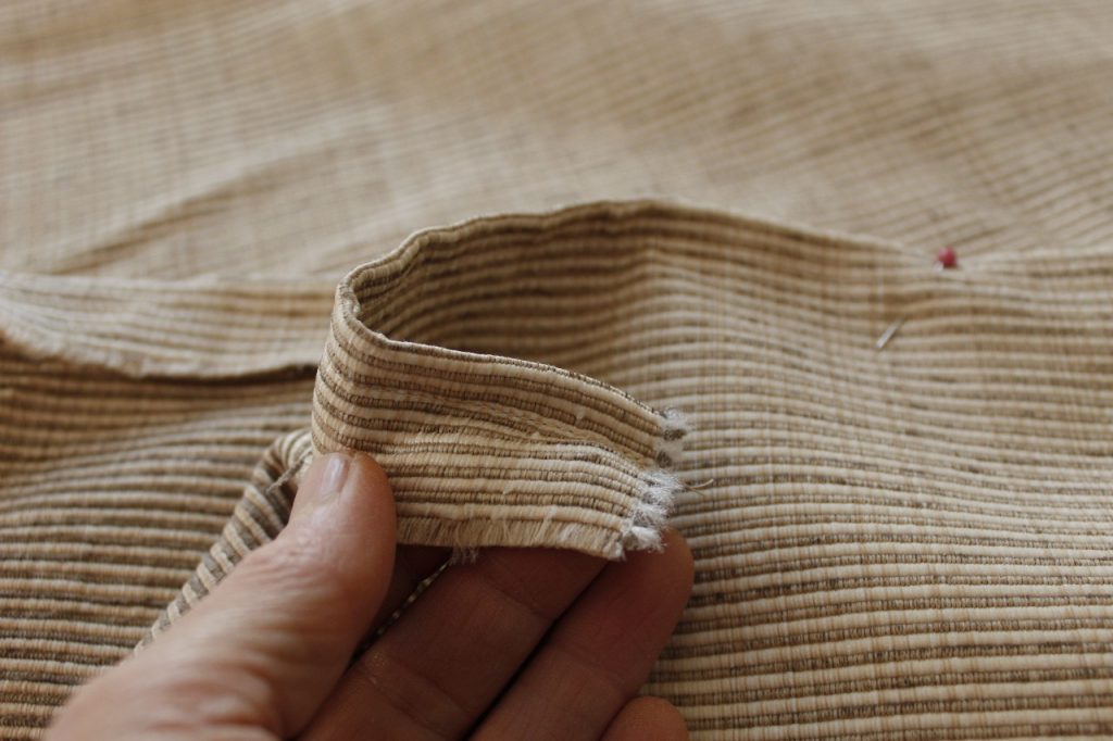 This image shows a hand holding the fabric in order for the reader to see the sewn edge.