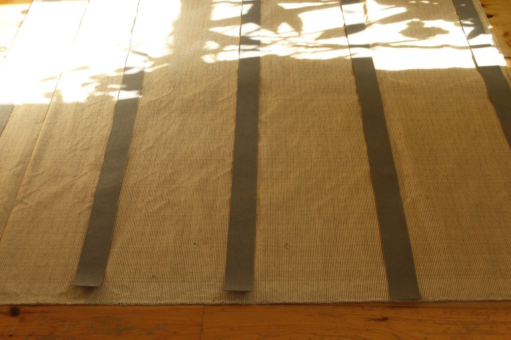 This image shows the rug tape lying on the rug, laid out to figure out the placement.
