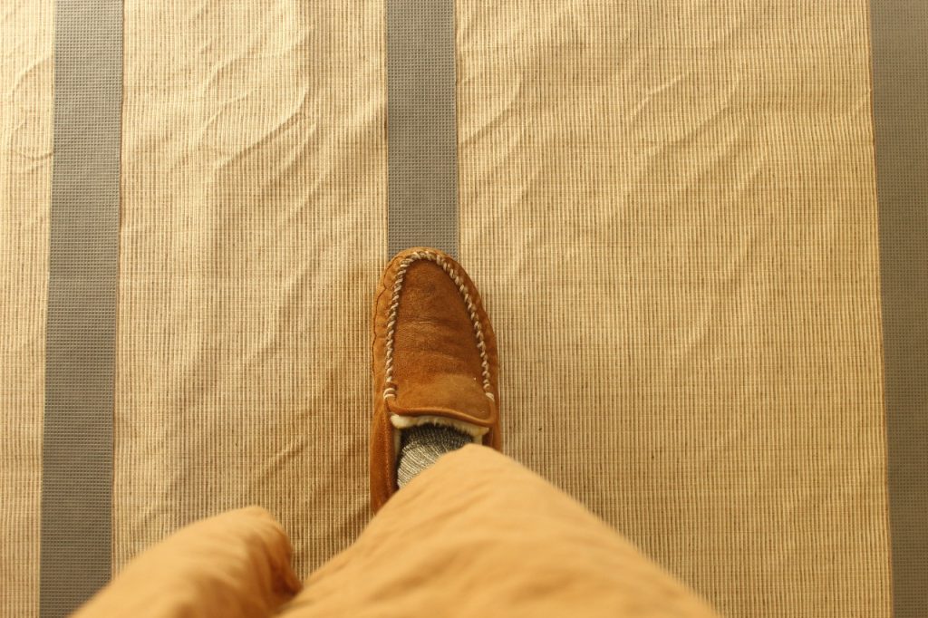 This image shows a woman's foot pressing down the rug tape to ensure its firmly adhered to the back.