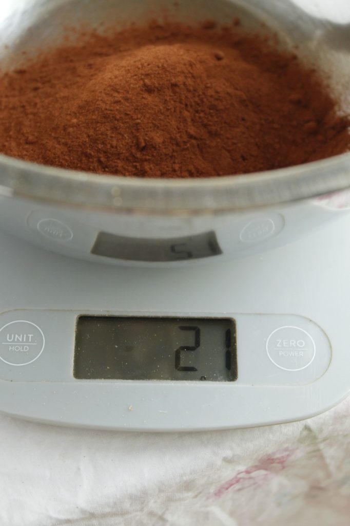 This image shows the madder root powder in a bowl on a scale being weighed. It's a deep muddy reddish brown color.
