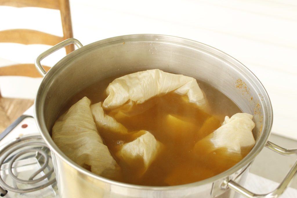 This image shows the silk fabric soaking in the dye pot with the symplocos to mordant the fabric.