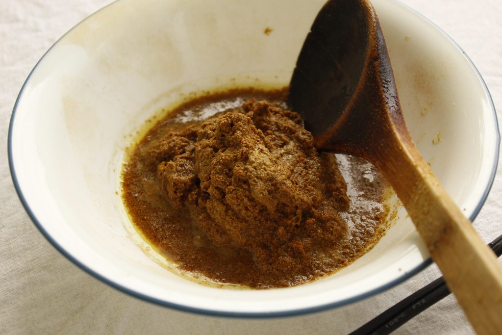 This image shows the dried symplocos in the bowl with a little water and stirred with a wooden spoon.